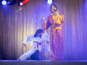 Chanteuse interprètant une chanson en live pendant un spectacle de Noël pour enfants, accompagnée d'une mise en scène interactive