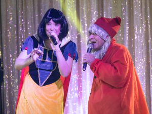 Scène du spectacle Arbre de Noël avec Blanche-neige et un nain chantant sur scène, animation musicale et interactive pour enfants