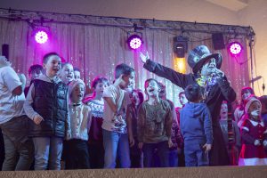 Enfants chantant et participant su cène lors d'un spectacle de Noël interactif avec les artistes, ambiance festive et familiale